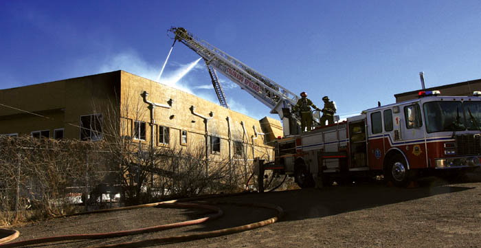 Firefighters shoot water onto the Johnson Heating and
Plumbing building, 2190 Busch Ave., in the early stages of
the wind-aided fire that eventually reduced it to rubble Jan.
5. A fallen power pole, shown leaning against the northwest corner of the building, is being investigated as a cause of the blaze.
Westside Pioneer photo