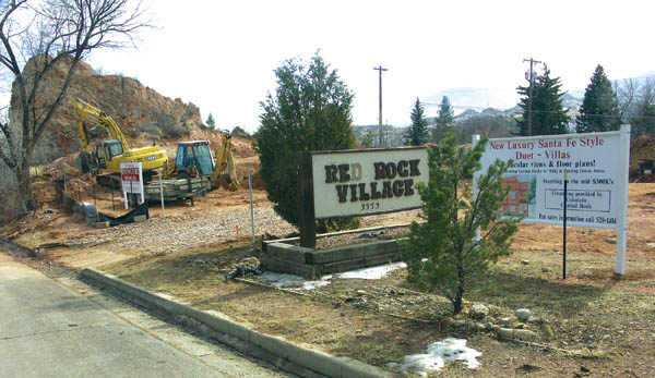 A photo taken from Kiowa Street shows a backhoe, the red
rock formation, the old Red Rock Village sign (a holdover
from when the property had several older cabins for rent)
and a sign for the infill duplex development advertising
new luxury Santa Fe Style Duet - Villas. 
Westside Pioneer photo