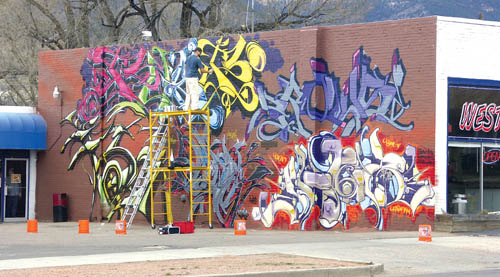 A Westside artist who goes by the name of Fuse
spray-paints his signature as part of the new mural that he
and six other grafitti-style artists recently started creating
on the east wall of the West Side Tattoo building. 
Westside Pioneer photo