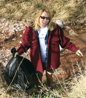 Cynthia McGrath cheerfully drags a full bag of trash up from Douglas Creek during the Holland Park Community 
Association clean-up effort April 26.
Westside Pioneer photo