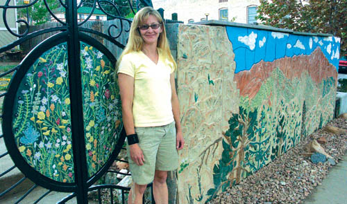 Sherry Bennett stands in front of the clay mural that now
decorates her homes concrete wall facing onto Pikes Peak
Avenue next to the Old Colorado City Library. The flowers
in the custom-made gate to her right were also part of the project.
