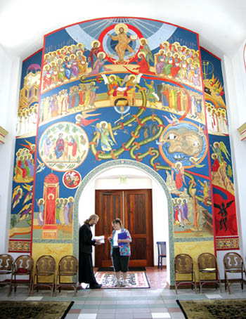 Father Anthony Karbo talks with a member of his
congregation at a doorway between the anteway and the
inner sanctuary. Symbolic religious iconographics adorn the
wall  part of an ongoing interior illustration project.
Westside Pioneer photo