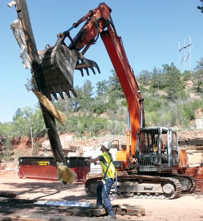 A trackhoe lowers one of several large beams salvaged
from the former Bock family garage/bomb shelter during the demolition of the building at Red Rock Canyon Open Space
this week. City Parks hopes to find 20 good beams to use in a new open-air pavilion to be built nearby, on the site of
the former Bock house, which is also being torn down in the project.    
Westside Pioneer photo