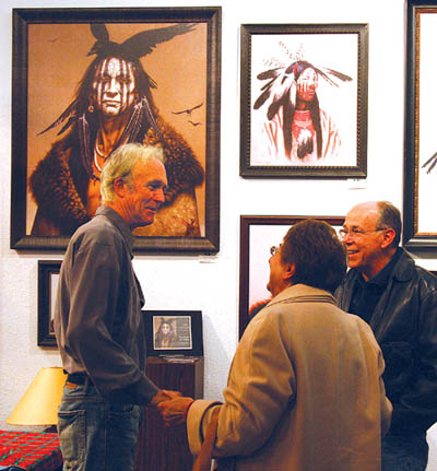 Standing in front of  gicles and prints of some of his paintings, Kirby Sattler meets with well-wishers during his
first public appearance in 14 years Dec. 5 at Pine Creek Art Gallery. 
Westside Pioneer photo